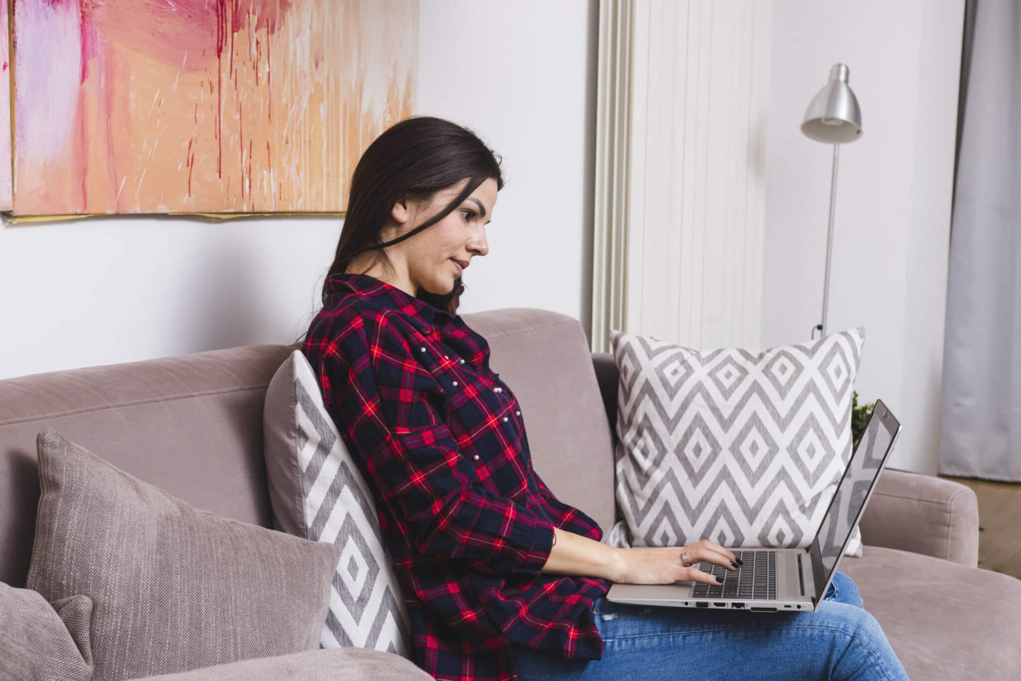 young-woman-busy-using-laptop-sitting-sofa